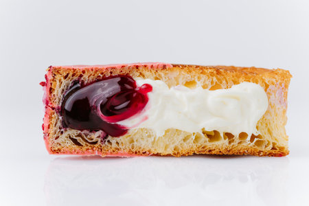 Pink glazed croissant roll with cream and cherry filling isolated on white backgroundの写真素材