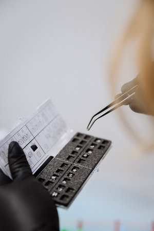Orthodontic bracket kit with placement chart and tweezers, gloved hands, clinic closeupの写真素材