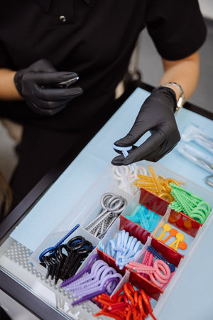 Orthodontic elastics and power chains selected with pliers in dental clinic, closeup