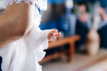 Newborn foot in christening gown during baptism, tender moment with soft bokehの写真素材
