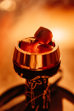 Glowing hookah coals in a metal bowl, warm bokeh bar lighting, macro closeupの写真素材