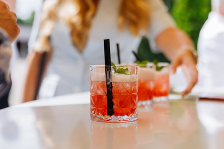 Hand reaches for a berry fizz cocktail in cut glass with mint, outdoor summer eventの写真素材