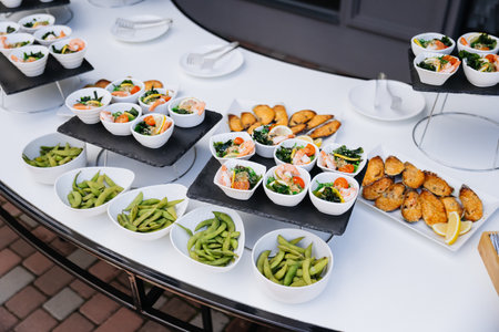 Catering spread with edamame, shrimp salads, and baked mussels on elegant displayの写真素材