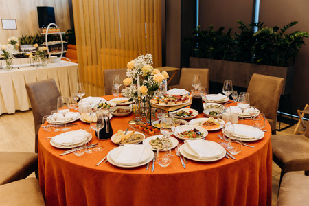 Elegant banquet table with floral centerpiece, candles and appetizers in restaurantの写真素材