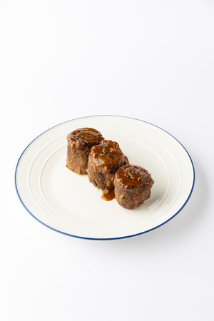 Beef roulade slices with rich gravy on white plate, isolated studio food photoの写真素材