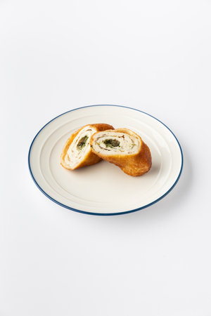 Sliced chicken roulade with herb butter filling on plate, isolated on white backgroundの写真素材