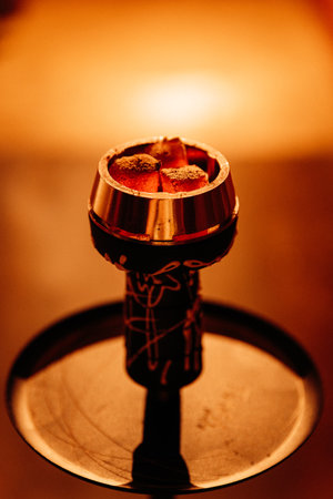 Glowing hookah coals in a metal bowl, warm bokeh bar lighting, macro closeupの写真素材
