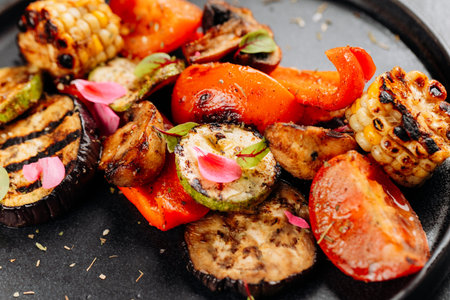 Colorful grilled vegetables with char marks on black plate, close-up, healthy vegetarian dishの写真素材
