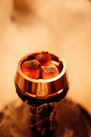 Glowing hookah coals in a metal bowl, warm bokeh bar lighting, macro closeupの写真素材