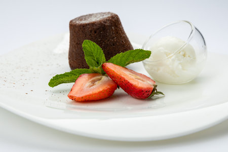 Chocolate lava cake with vanilla ice cream and strawberries on white plate, top viewの写真素材