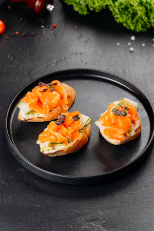 Top view of salmon canapes on baguette with cucumber and cream cheese on black plateの写真素材