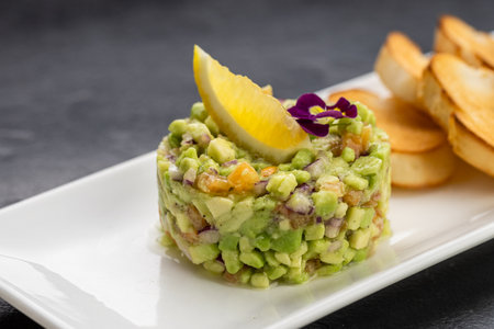 Avocado tartare with toasted baguette slices on white plate, gourmet appetizerの写真素材