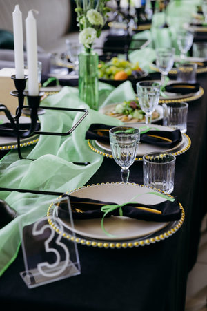 Elegant black and green tablescape with candles, place settings and glassware