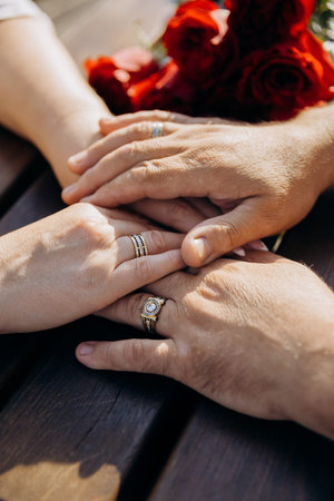 Man holding womans hands with wedding ring, romantic moment with red roses, closeup, copy space