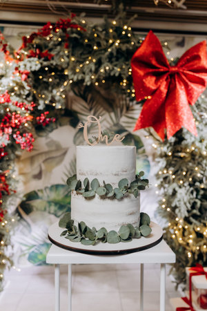 First birthday cake with One topper and eucalyptus, wreath backdrop, copy space