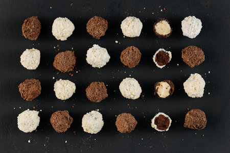 Assorted coconut and cocoa truffles on black slate, flat lay
