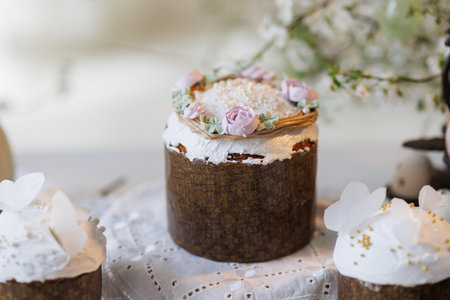 Easter cakes and eggs on lace table with spring blossom branches, soft daylight