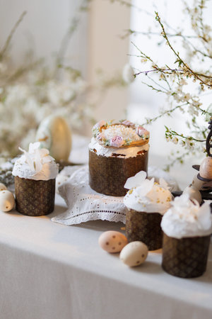 Easter cakes with icing and eggs on spring table, soft light