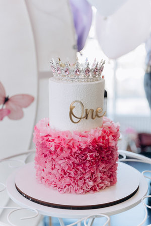 Princess first birthday cake with crown and One topper, pink balloons decor, party backdropの写真素材
