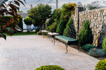 Elegant stone wall patio with wrought iron benches in landscaped gardenの写真素材