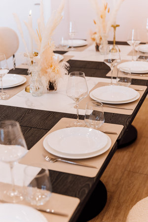 Elegant banquet table set with wine glasses, candles and pampas decor