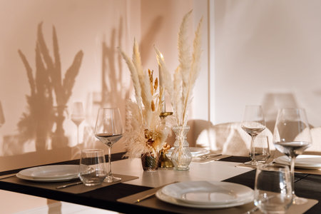 Warm candlelit table setting with pampas centerpiece and wine glasses
