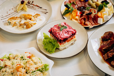 Traditional layered salad and gourmet dishes served on festive restaurant dinner table
