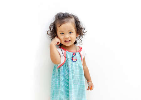 Asian Cute girl smile with curly hair, aged twenty two months in green striped dress.