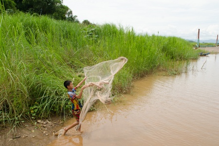 HOUAY XAI HARBOR,BOKEO,LAO PDR  JUNE 10 ; Unidentified boy is throwing his net for fish in Mekong river on June 10,2013 at Houay xai harbor, Bokeo , Lao pdr のeditorial素材