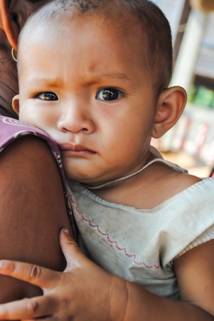 ALAVAN, LAO PDR – FEBRUARY 09 ;Unidentified child is on the arm of mother at the villagers meeting...