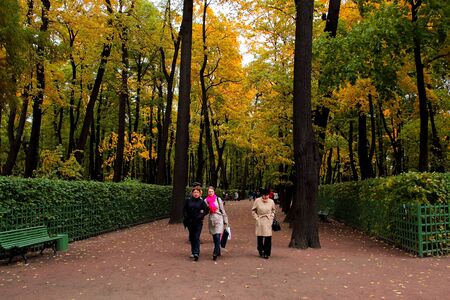 ST. Petersburg, October 4, 2018. Autumn in a city park. Colorful leaves in the sun. People walk along the paths of the park. The beauty of nature scene in the fall seasonのeditorial素材