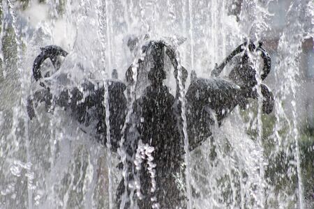 Abstract photo of the fountain, shot close-up. Water flows down the granite bowl.の写真素材