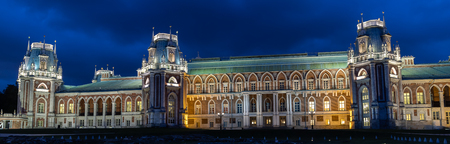 Night panorama of the magnificent old Gothic castle of red brick illuminated by yellow lights against the dark blue sky.のeditorial素材