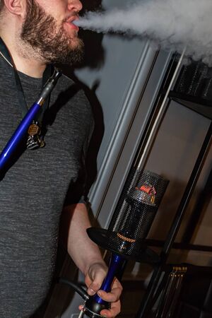 Close-up of a man smoking a traditional hookah pipe, man exudes smoke, hookah lifestyle and smoking...
