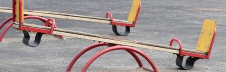 New modern bright colorful yellow and red empty toy swing. Swing on the Playground on a bright Sunny day. An ideal place for children's outdoor activities.の写真素材