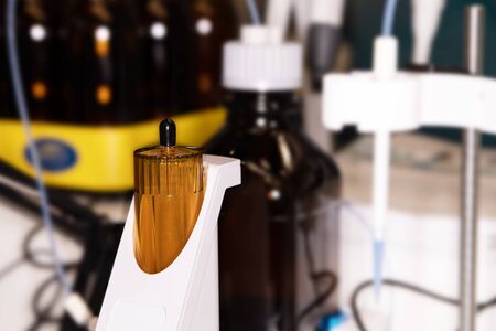 Close-up of a laboratory glass flask with a yellow liquid on a laboratory table for experiments. The...