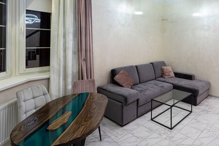 Modern interior of a large and cozy living room with a sofa and a table by the window. Mockup on the...