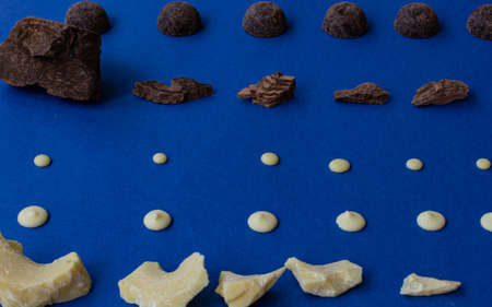 Pieces of natural dark chocolate and white chocolate on a blue background