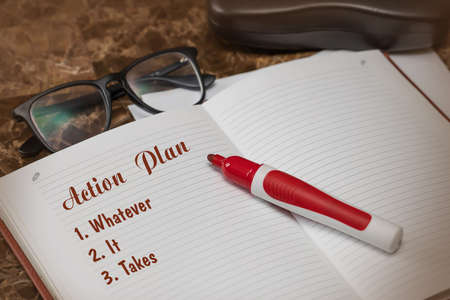 Action plan text on paper in open diary with glasses, colorful stationery pen on marble work table, business and finance conceptの写真素材