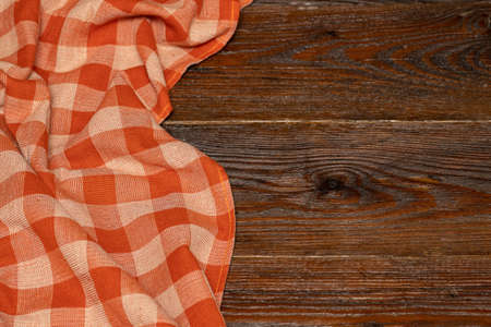 Checkered linen tablecloth on a wooden background. Brown wooden table. Selective focus. Copy space. Place for food and drink. Picnic and thanksgiving day concept. Restaurant, menuの写真素材