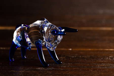 The bull is the symbol of 2021. Zodiac sign Taurus. Glass figurine on a brown wooden background. Close-up, selective focus.の写真素材