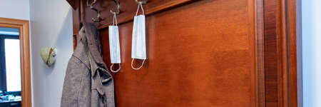 New normal. Medical disposable masks on a hanger in the hallway next to the coat. Rules of conduct during the coronavirus epidemic.の写真素材