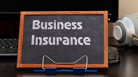 Business Insurance Services Concept. The text is written on a chalk board located at the workplace near the computer.の写真素材