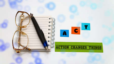 Action changes things. Acronym ACT. Nearby is a notepad, glasses and a pen.の写真素材