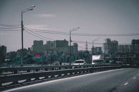 A toned image of a cityscape with sun flares. Car traffic on the road in summer in Moscow. The...