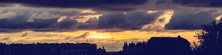 Sunset cityscape. Silhouette buildings against an orange sky. City view at sunset. Bright orange sky at sunrise. Dramatic sky with purple clouds. Golden sky. Sundowners in the cityの写真素材