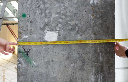 Measuring tool in hand against the background of a concrete wall, copy space for text and design....