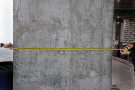 Measuring tool in hand against the background of a concrete wall, copy space for text and design....