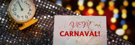 Vem Carnaval is Carnival is coming in Portuguese language. Popular Event in Brazil. Festive Mood. Carnival announcement against the background of shiny sequined fabric, clock and colorful lightsの写真素材