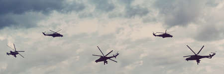 Silhouettes of military helicopters in the cloudy sky. Flight of the helicopterの写真素材